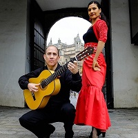 a man holding a guitar next to a woman in a red dress