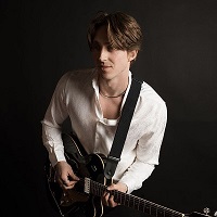 young man in a white shirt holding a guitar