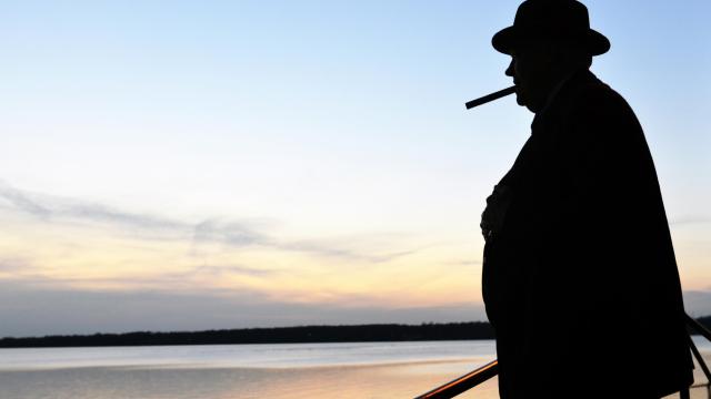 A man stands in silhouette against a sunset over the water