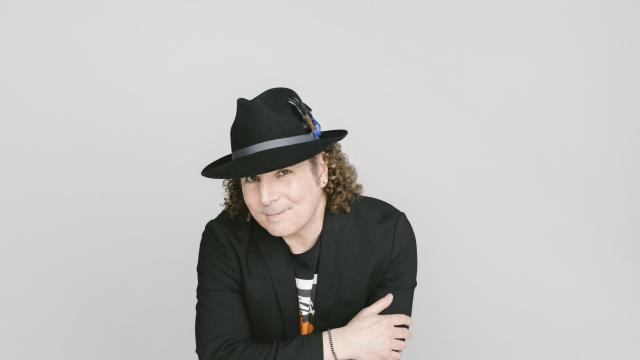 man with a black hat looking at thecamera smiling and holding his arms