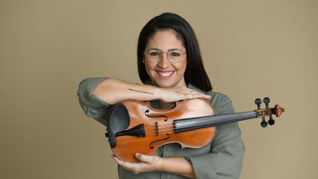 woman with dark hair holding a violin smiling