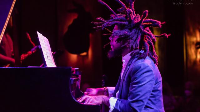 man with dreads playing the piano. the shot is taken from the left of him, making him in profile