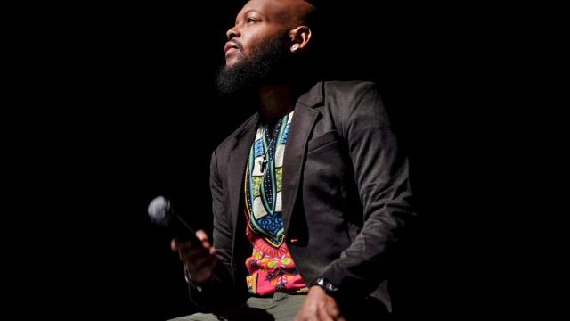 Man sitting in a dark room with a microphone looking off to the left