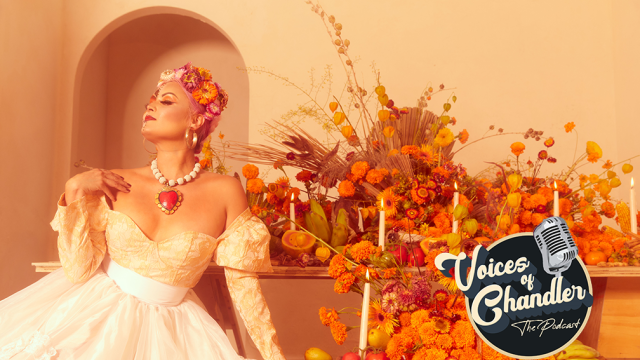 A woman sits in front of an abundant display of orange flowers