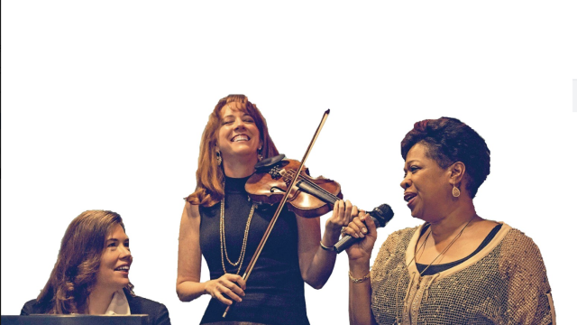 A pianist, violinist, and singer perform in front of a white background.