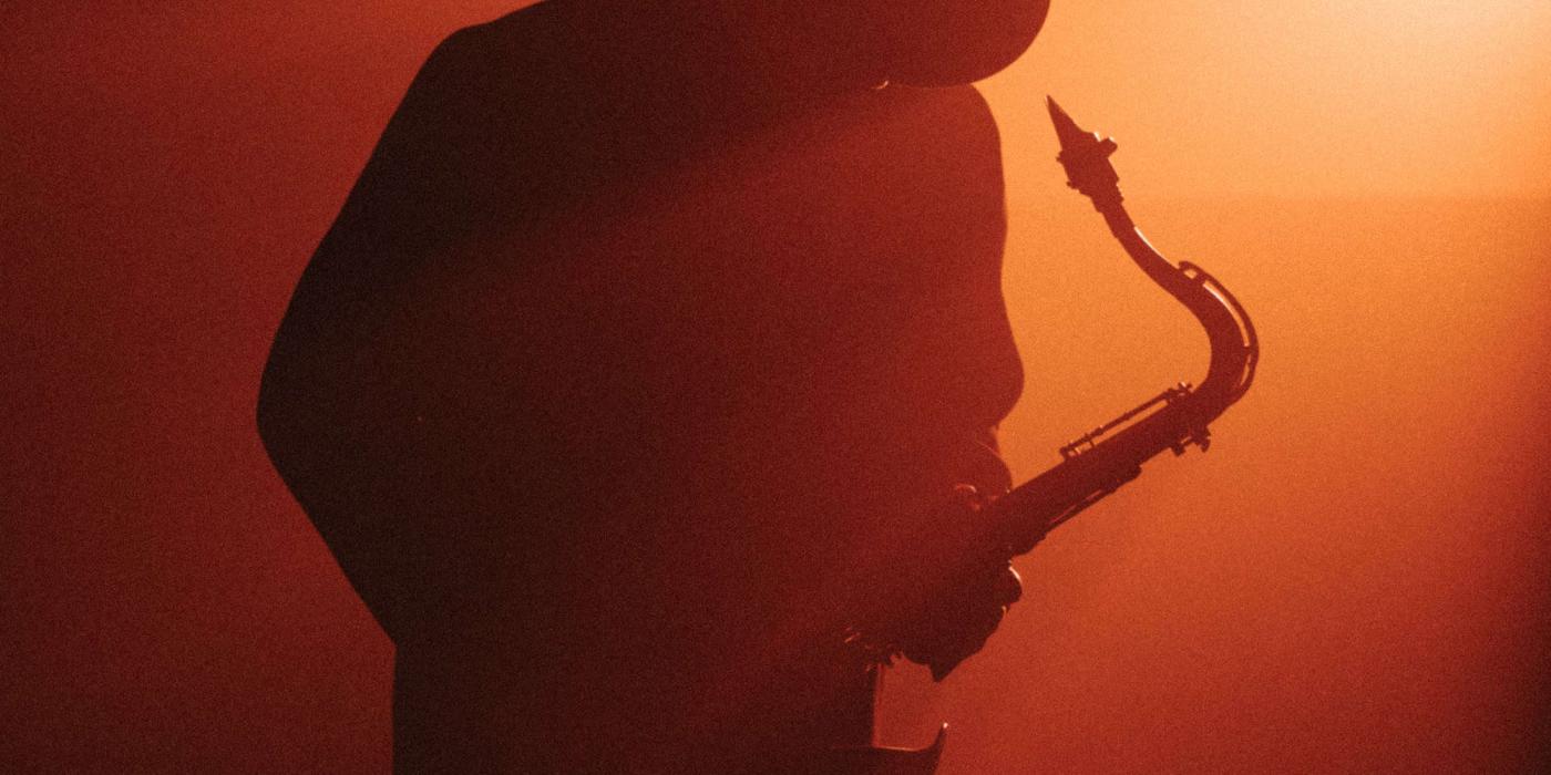 boney james plays his saxophone in a smoky room with red light