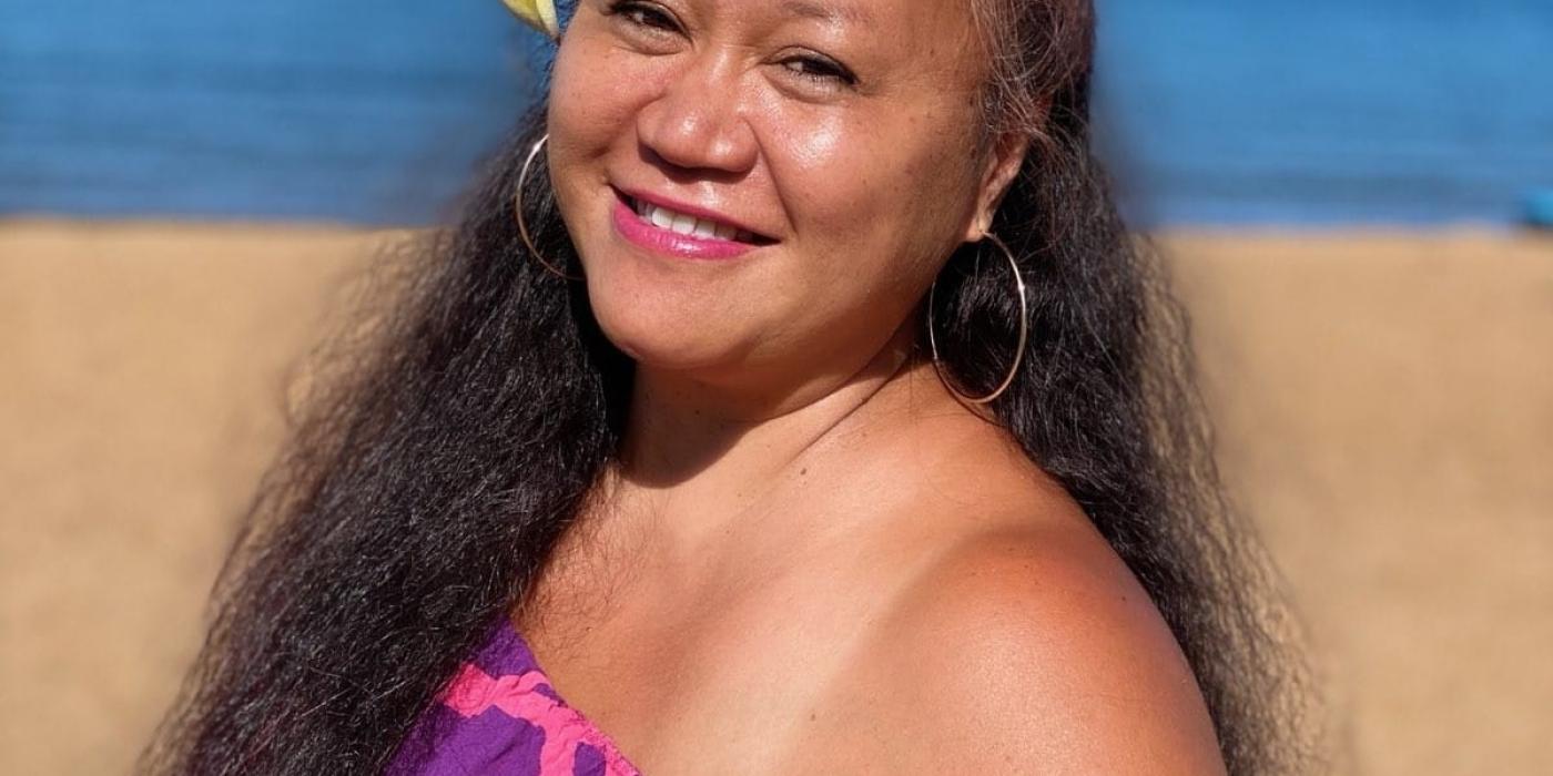 Kami Valdez on a beach wearing Hawaiian sarong with a flower in her hair.