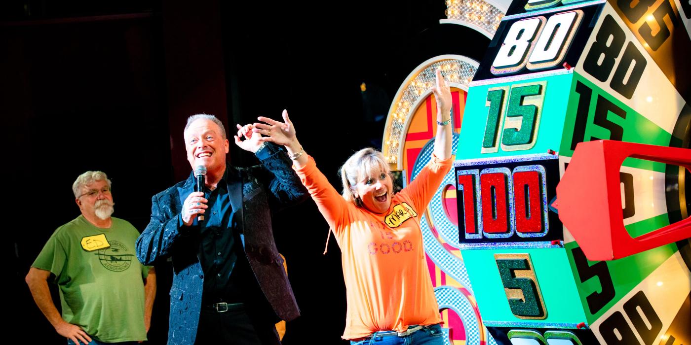 excited woman with her arms up looking at The Price is Right wheel 