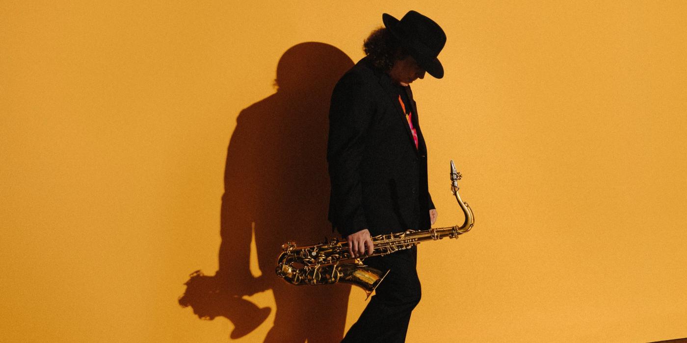 Boney James looking down while holding saxophone