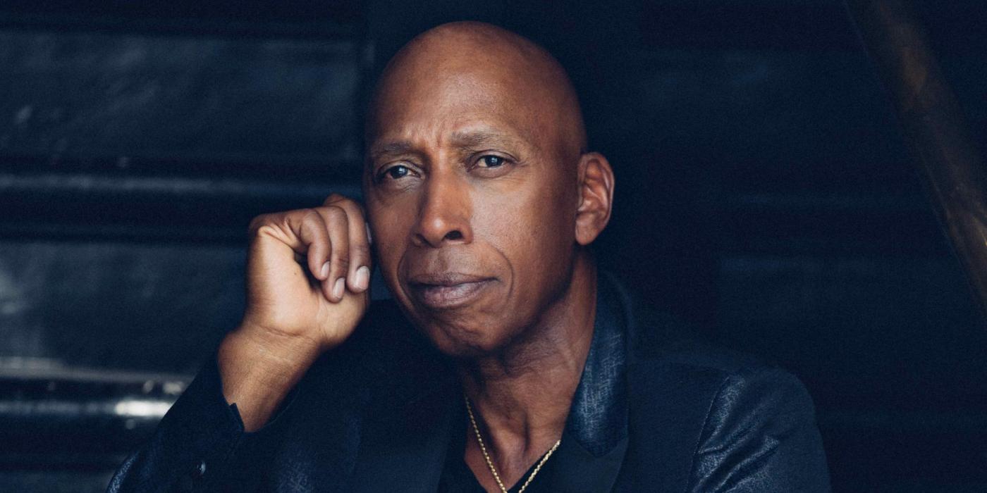 African male sitting on stairs, wearing all back clothing.