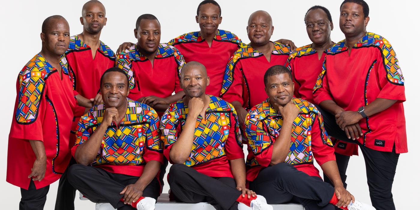 Group of African men wearing red shirts with colorful designs.