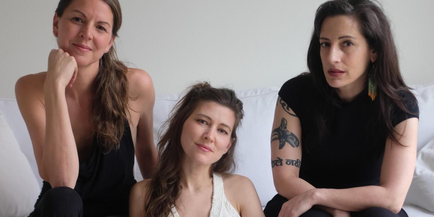 3 caucasian woman sitting on a white sofa.