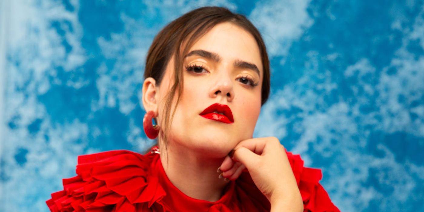 Woman in red dress sitting in front of a sky-like textured backdrop
