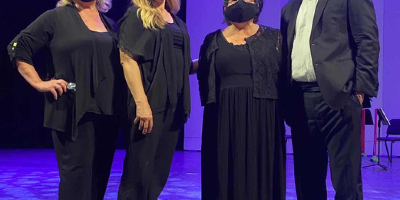 Four musicians, dressed in formal wear and masks, pose in front of a purple backdrop.