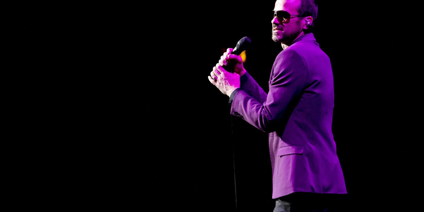 Performing on stage with purple jacket and sunglasses