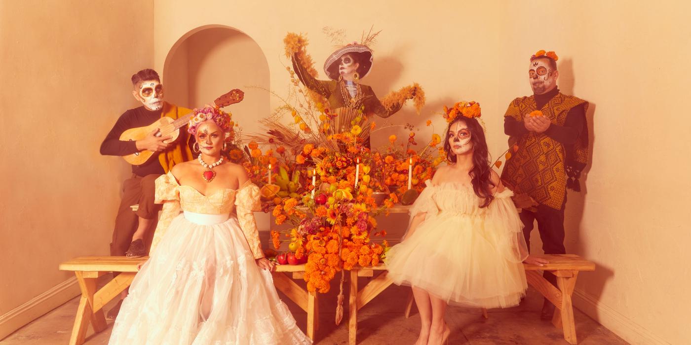 Five people pose, dressed in costumes and faces painted skeletons