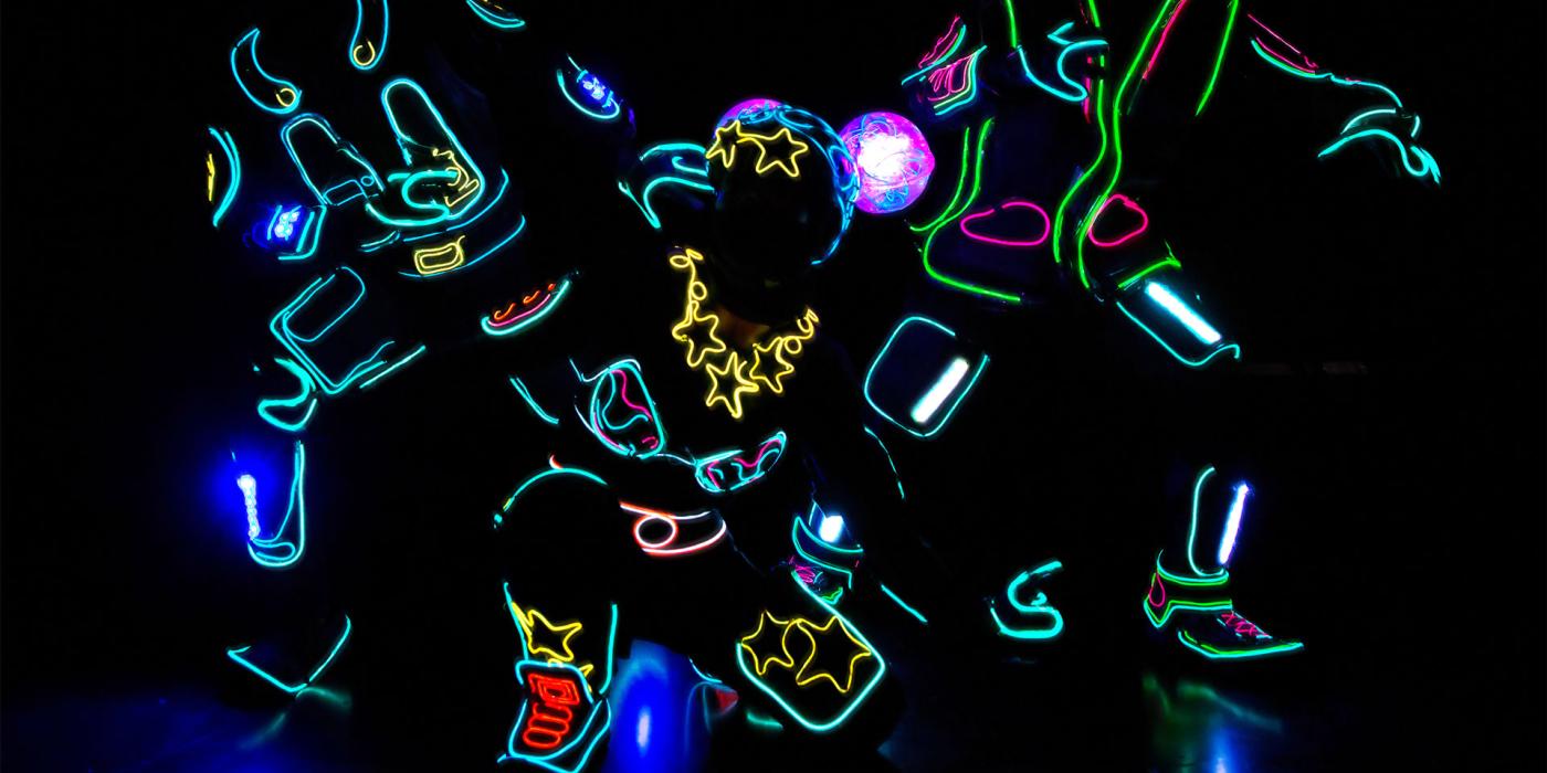 Three iLuminate performers lit as a cop, female super hero and bystander