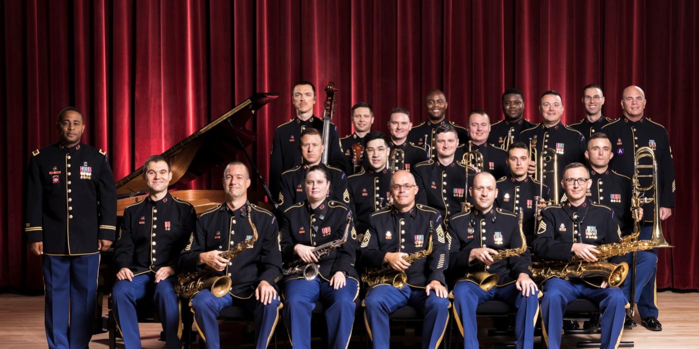group of men in uniforms surrounding a piano and in front of a red curtain