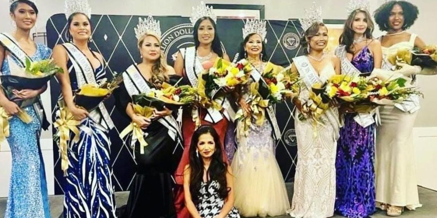 group of women wearing dresses, holding flowers, wearing crowns and looking at the camera smiling