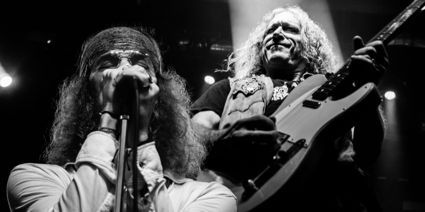 Black and white "album cover" style graphic with singer and guitar player on stage and the words "Get The Led Out"
