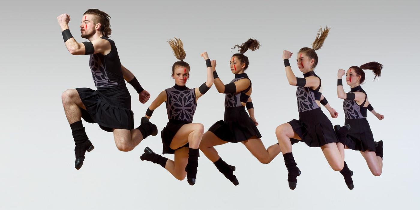 Five Members, one male and four females, of Trinity Irish Dance Company leaping forward through the air