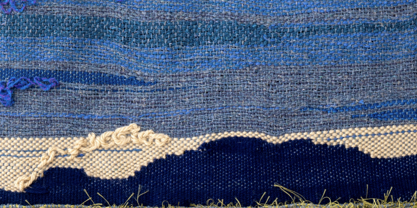fabrics of blue white and green/yellow making up an image of a mountain or hill in almost darkness