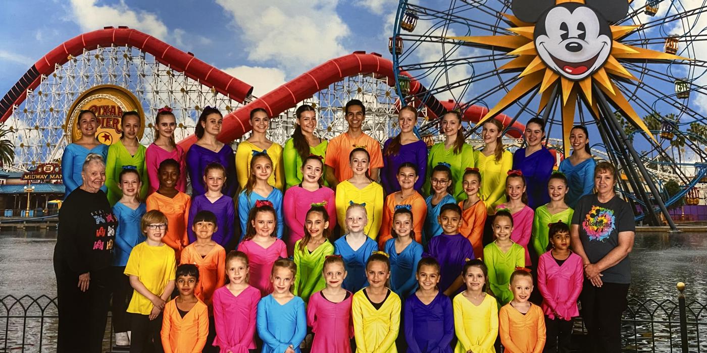 Tempe Dance students dressed in different primary color t-shirts posed in front of Disney roller coaster