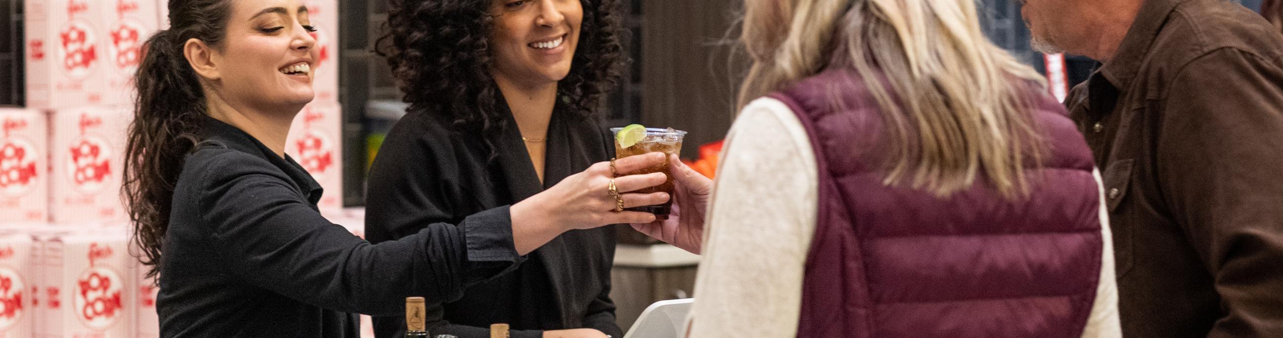 two bartenders serving customers 