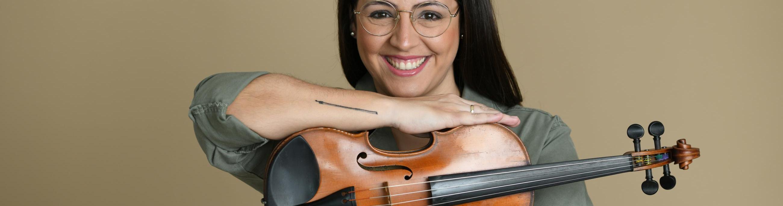 woman with dark hair and glases holding a violin 