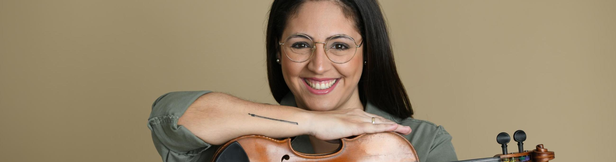 woman with dark hair holding a violin smiling