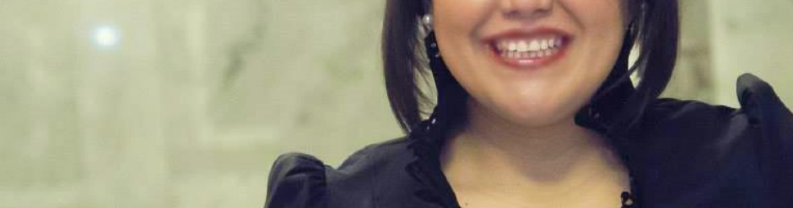 A woman in a black blouse and silver earrings smiles at the camera.