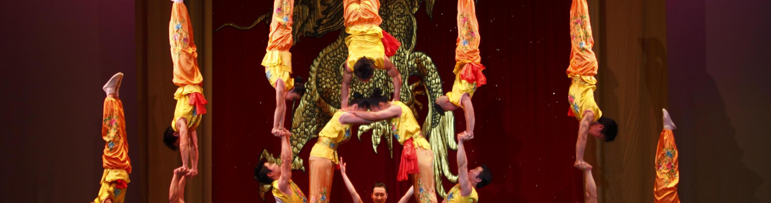 people holding up one another in handstands, making a triangle