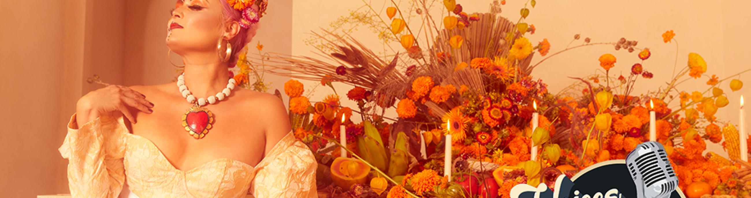 A woman sits in front of an abundant display of orange flowers