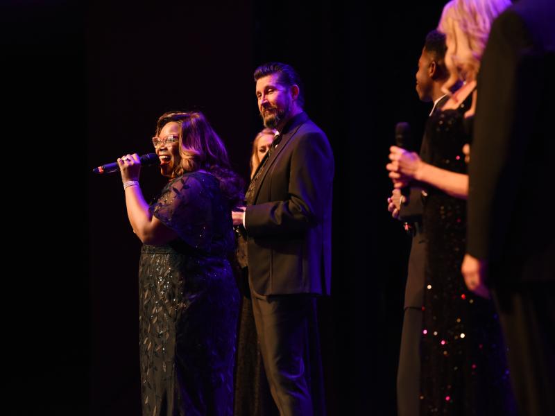 group of singers performing on stage, one singer performers in the forefront