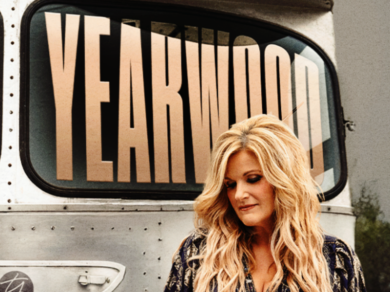 Blonde woman standing in front of silver bus that says Trisha Yearwood
