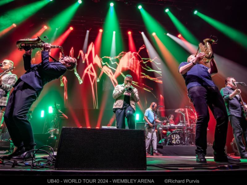 singer and two saxophonists on stage with green and red stage lights