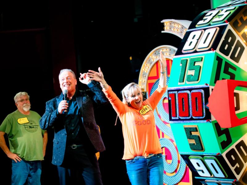 excited woman with her arms up looking at The Price is Right wheel 