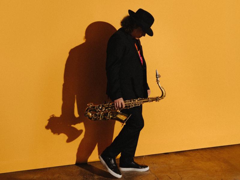 Boney James looking down while holding saxophone