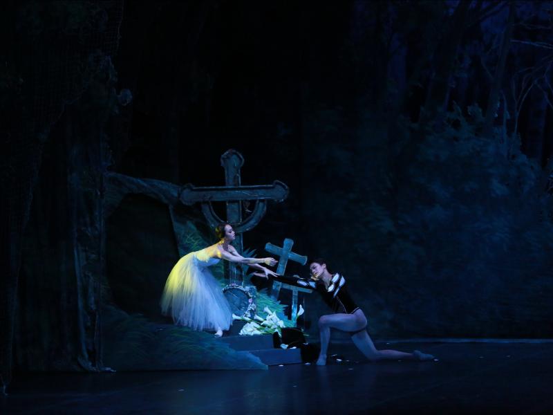 Woman and man hovering over crosses reaching for one another in ballet. 