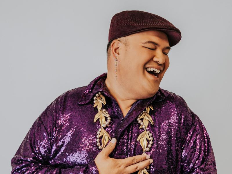 Polynesian male wearing a brown golf cap, purple sequins shirt with a beaded lay