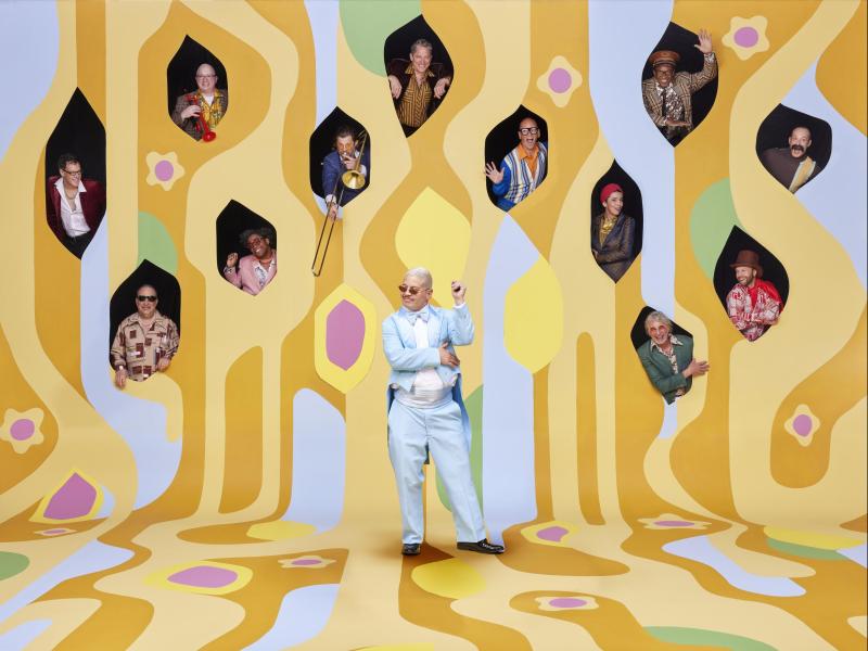 Pink Martini band members in cutouts of retro print wall