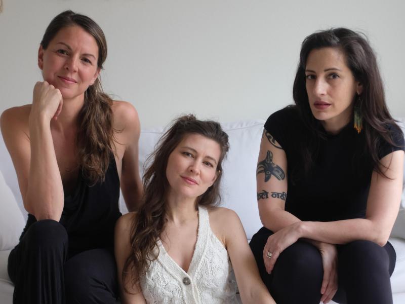 3 caucasian woman sitting on a white sofa.