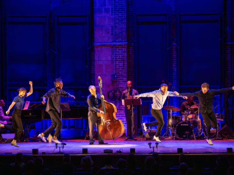 five dancers on a purple backlit stage