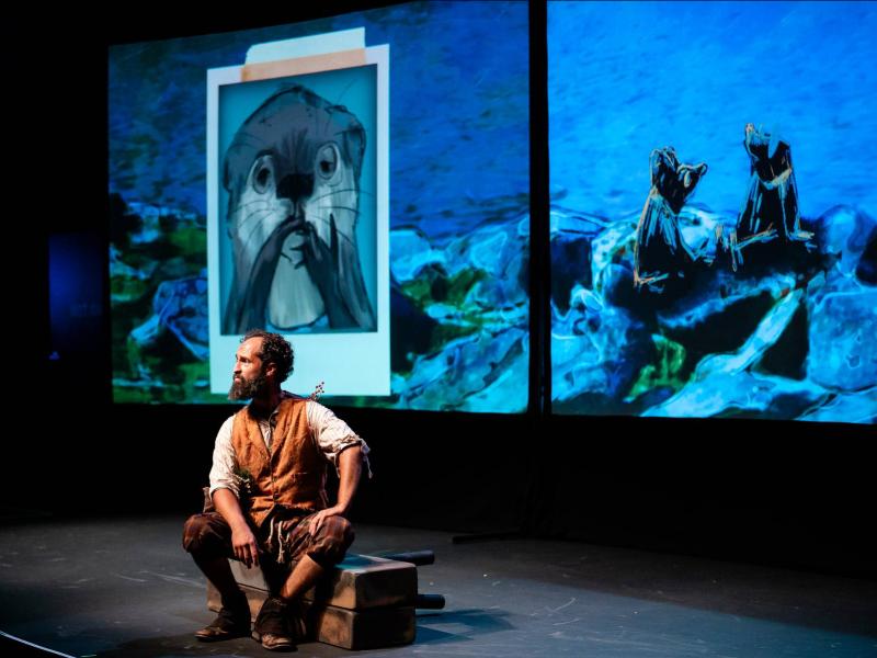 Man sitting on stage with a photo of otter on a projected screen