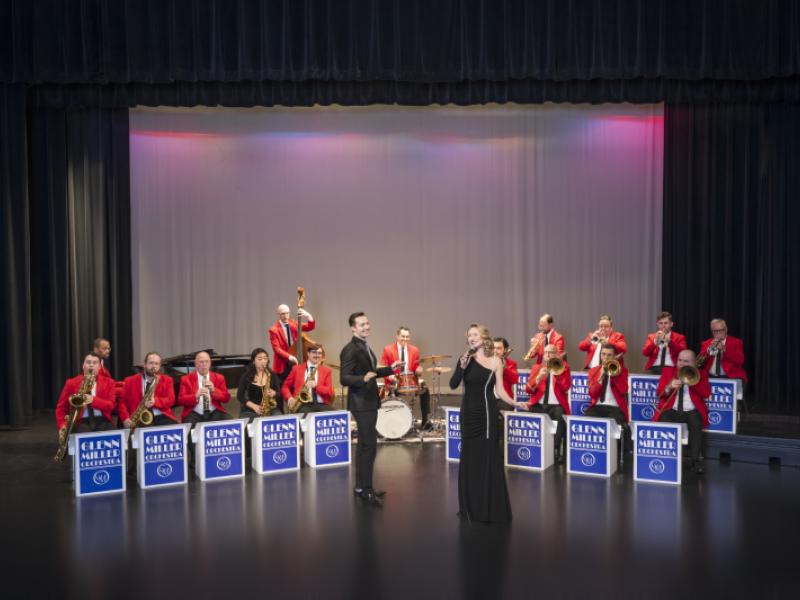 Man and woman singing in front of seated orchestra