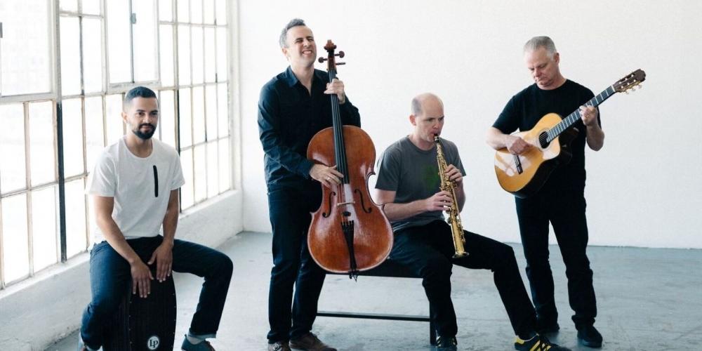 Four men play various instruments, including a bass, wind instrument, guitar and percussion