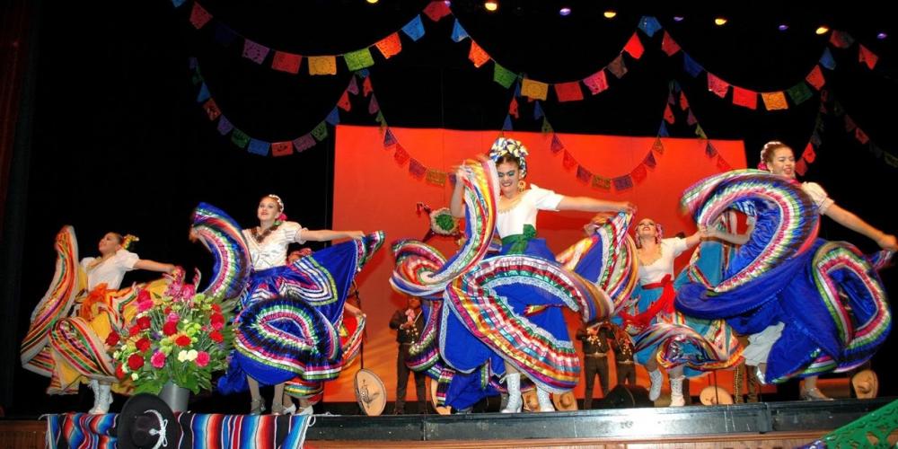 Dancers dresses in bright blue costumes swirl and swish their skirts