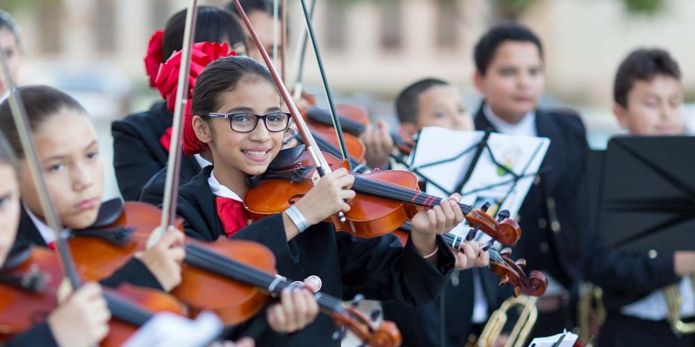 The camera focuses in on one violin student in a mariachi band