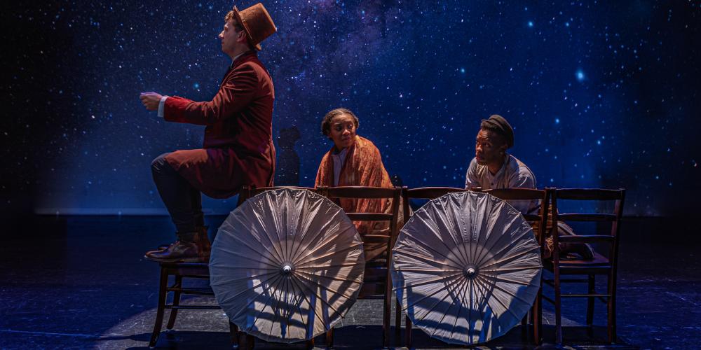 Three people sit in an imaginary wagon, umbrellas for wheels, with a starry night background