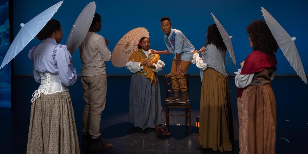 Five women with umbrellas listen to a young man tell his story